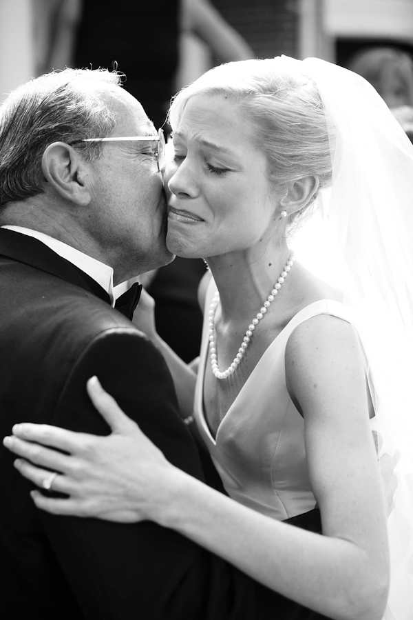 black and white photo of the father of the bride kissing the bride on her cheek as they dance - photo by North Carolina based wedding photographers Cunningham Photo Artists